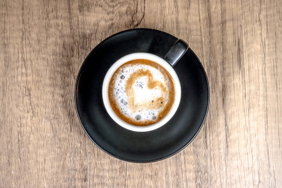 Latte con un corazón de espuma en una taza negra