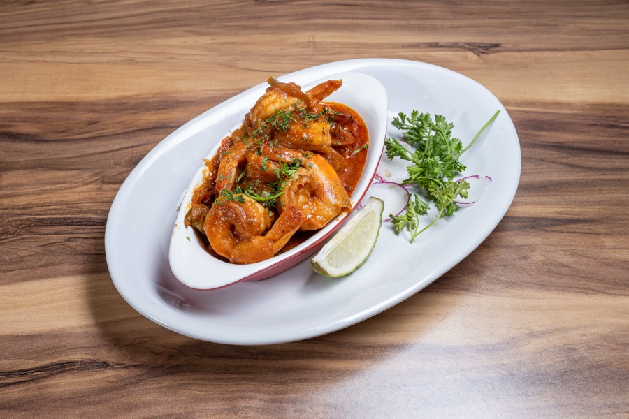 Camarones en salsa roja con hierbas en un plato blanco