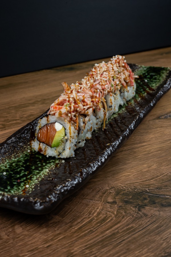 Rollo de sushi de salmón en un plato negro de piedra